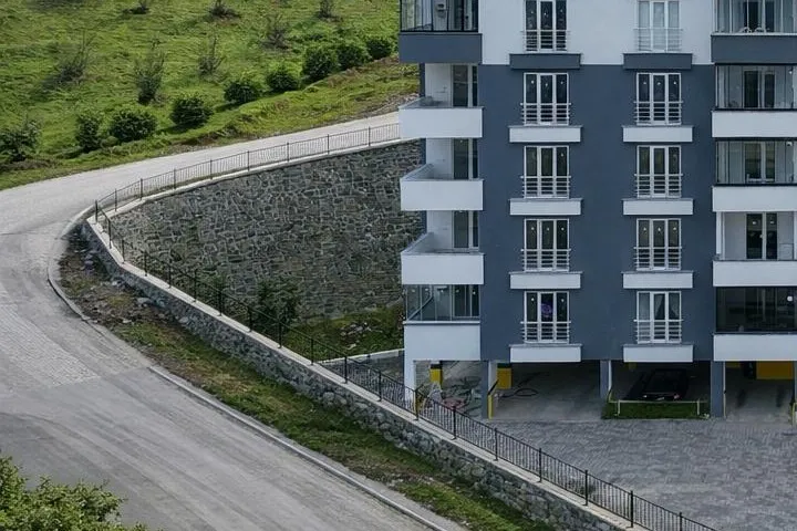 Güneş Apartmanı’na çıkan yol ve taş duvar, yeşil yamaç