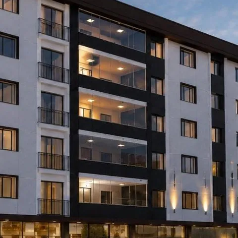 Tepe Apartmanı görselinde ışıkları yanan cam balkonlar